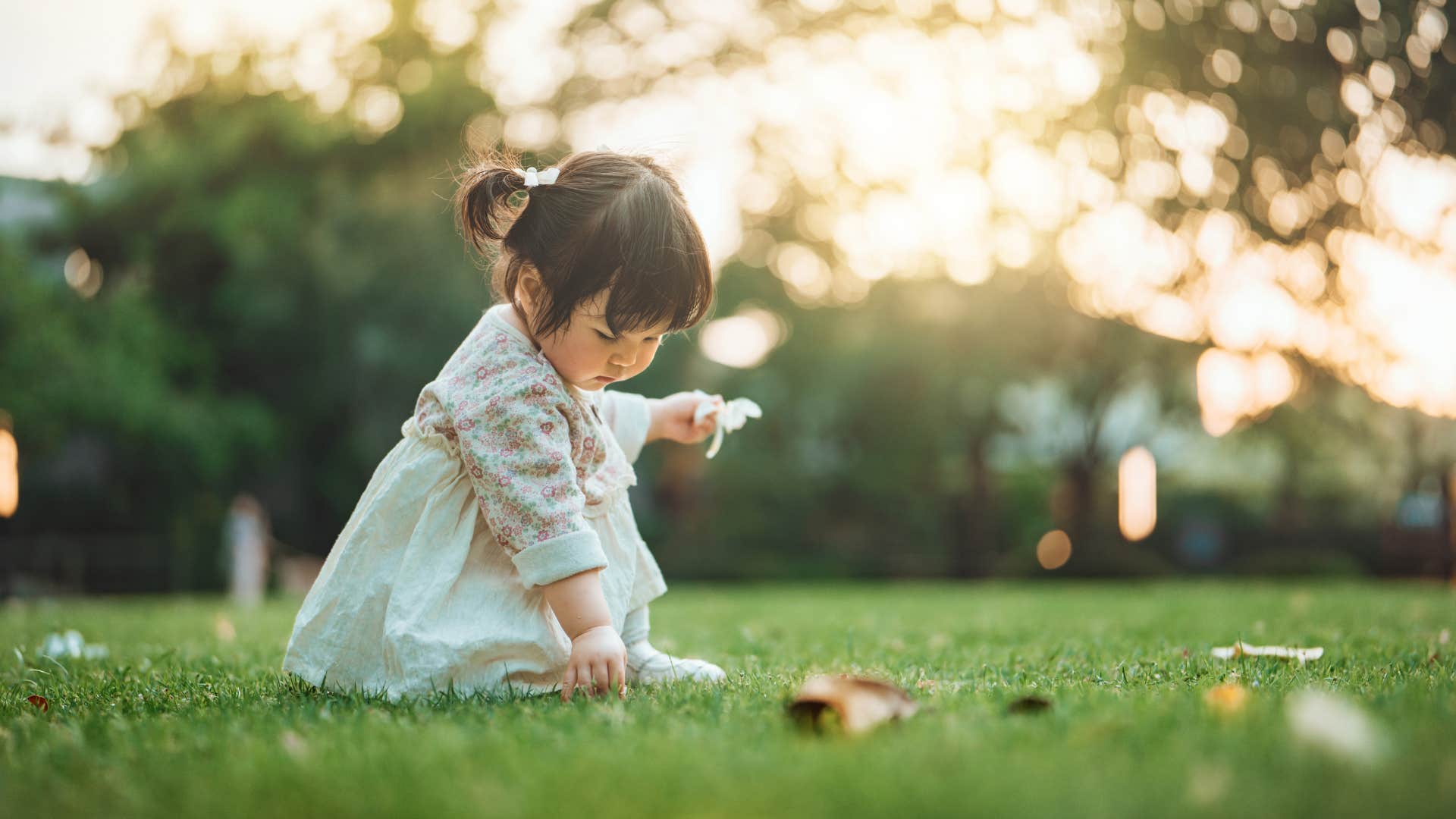 curious toddler daughter gathers leaves showing life skill to thrive