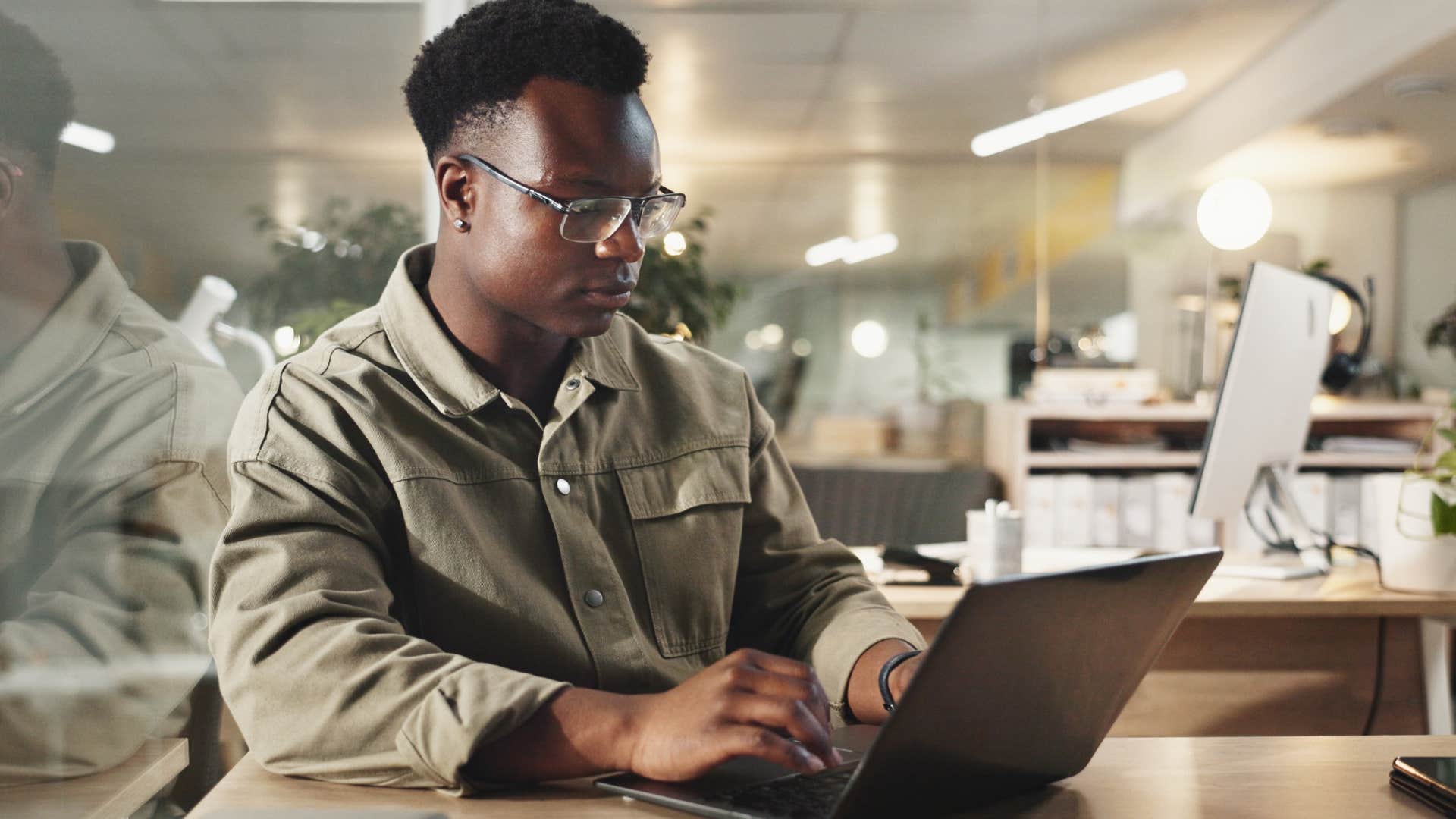 gen z man typing on laptop writing less by hand