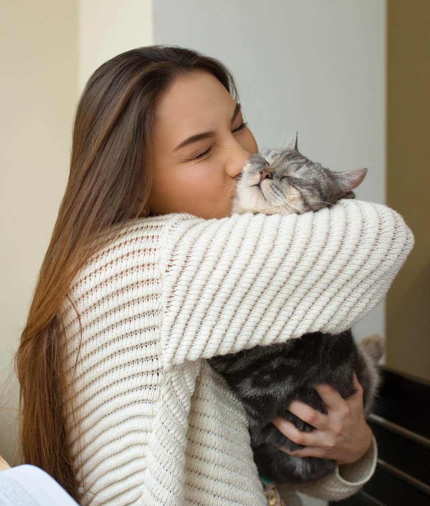 young woman snuggling and kissing cat has a reduced risk of heart attack