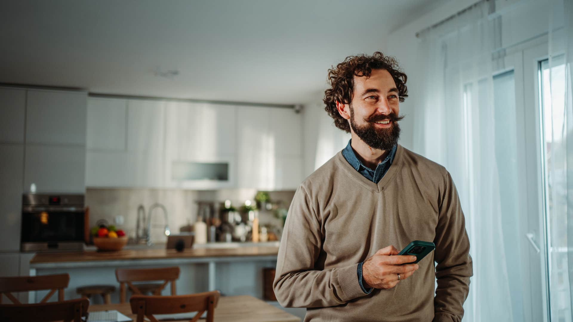 retired man at home holding his phone not having to perform