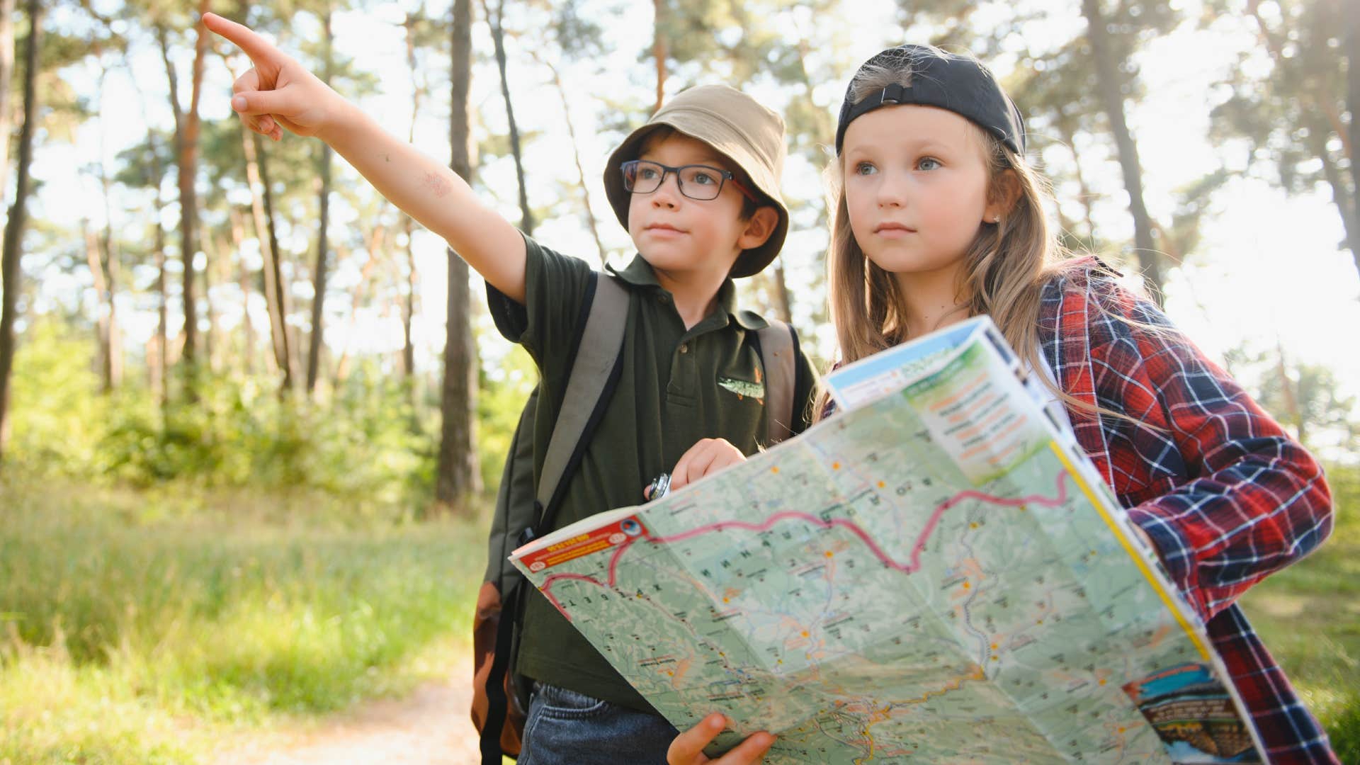 kids reading a physical map outside for directions