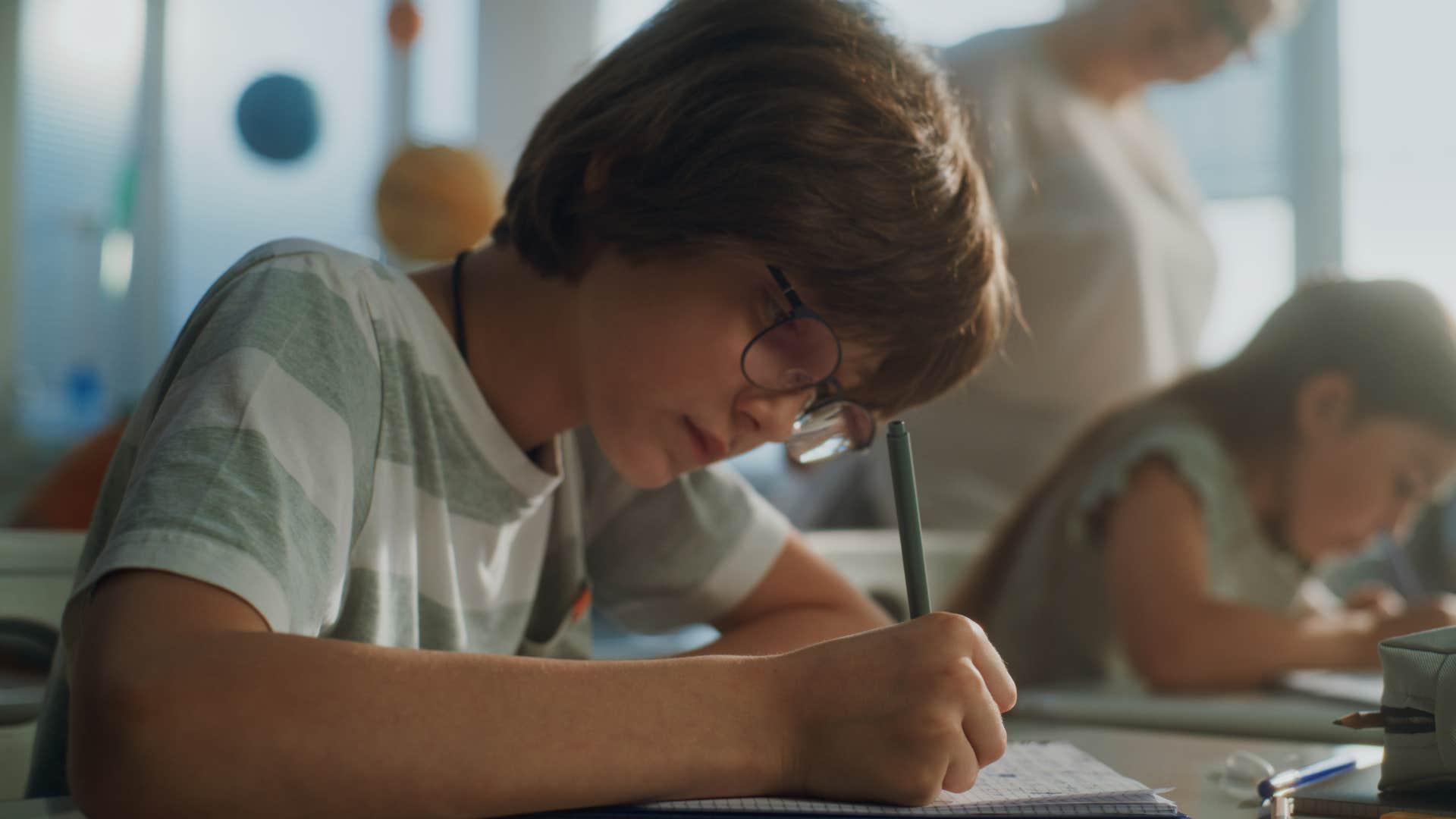 boy writing in cursive in the classroom