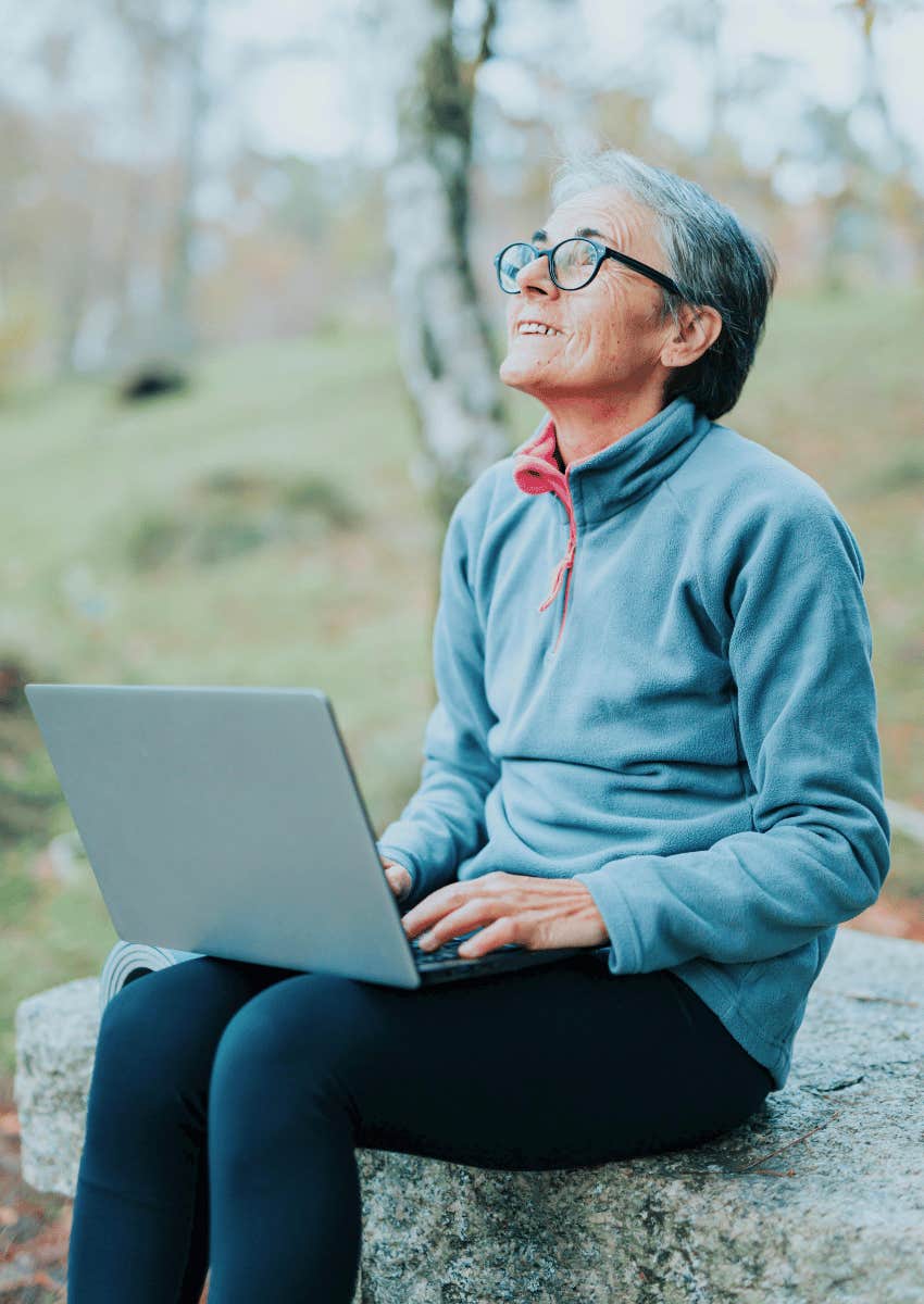 smiling older woman holding an open laptop