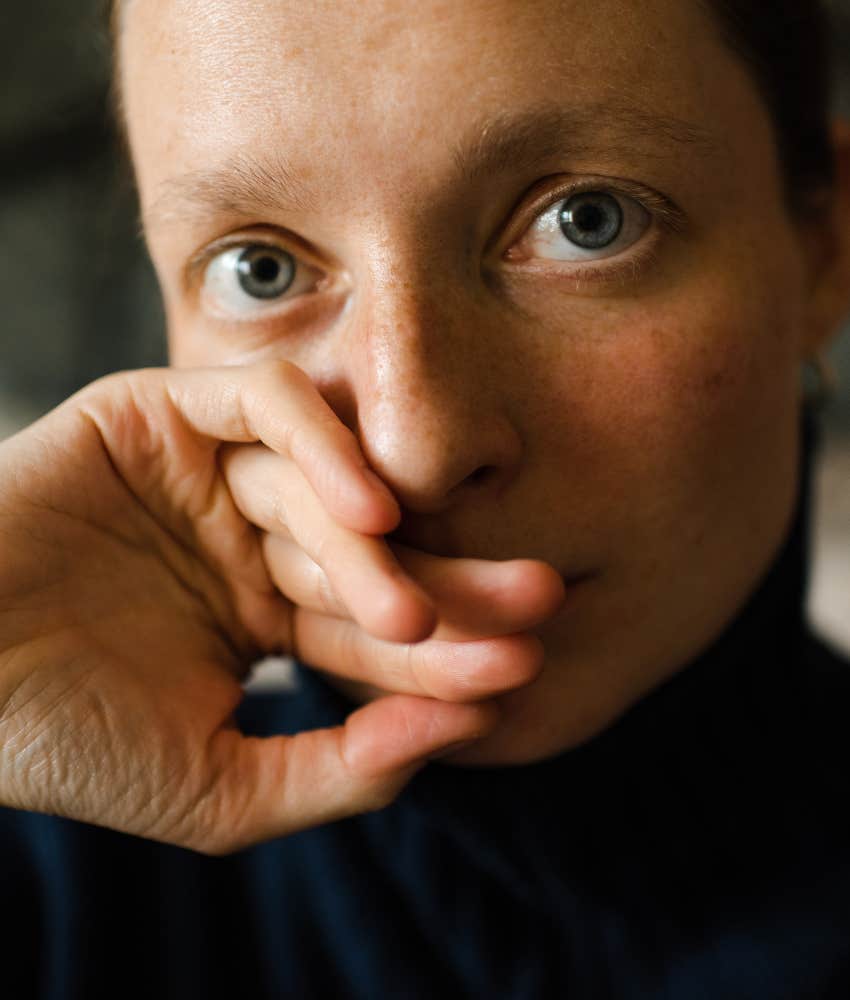 Serious person with hand over part of face showing they won't allow leaning in