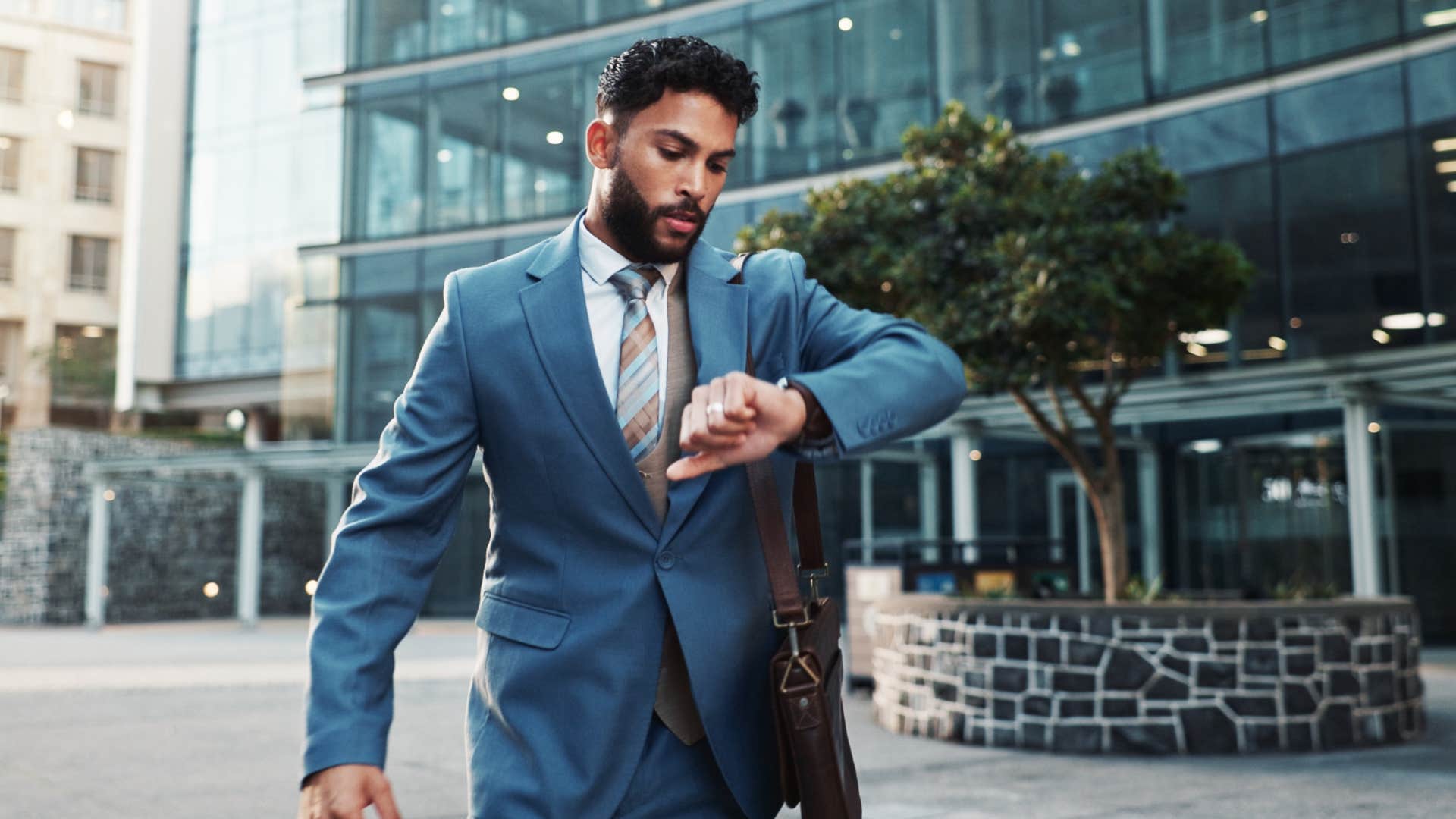 man in suit running slightly late as he stares at watch
