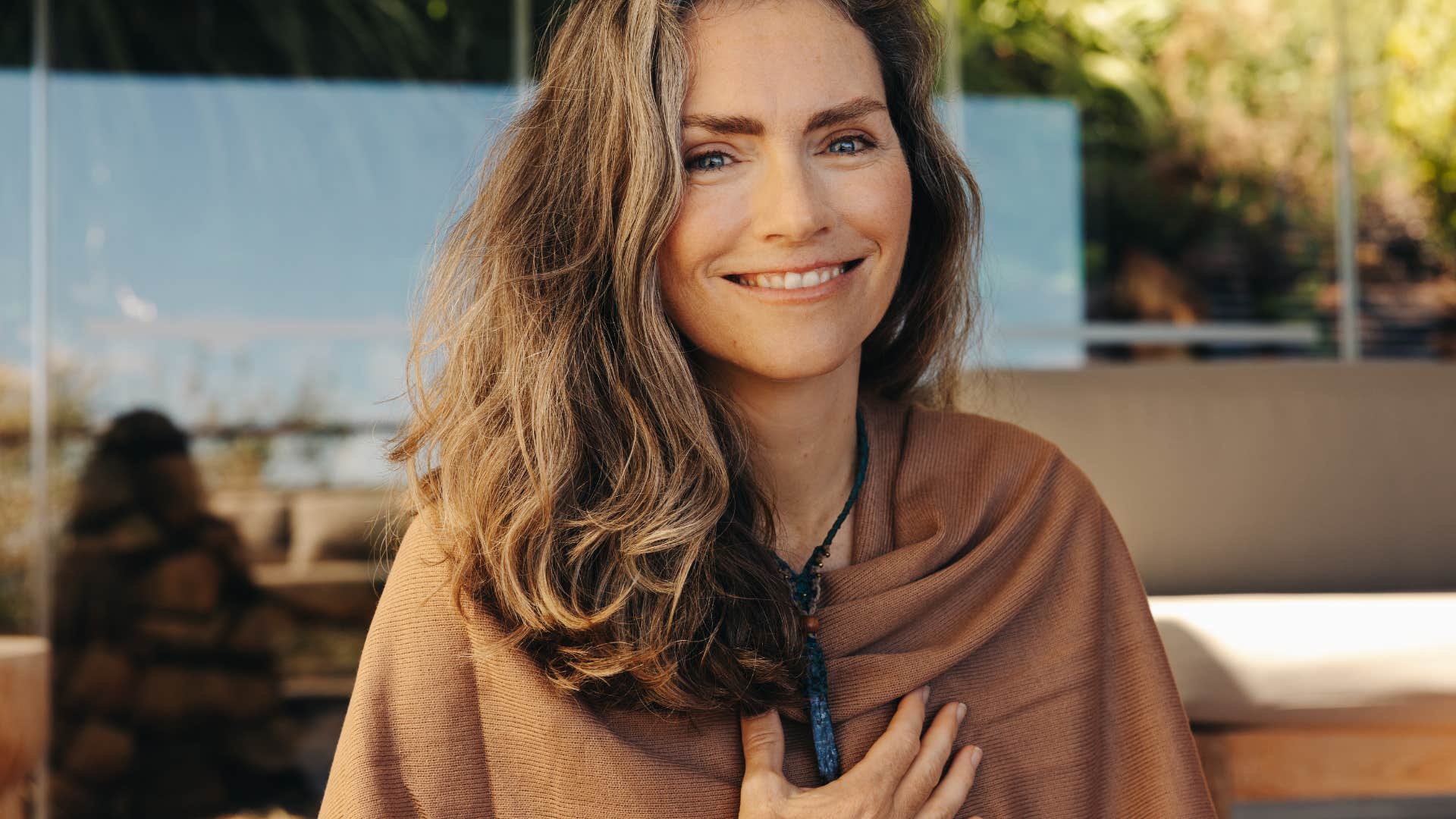 Smiling woman touches necklace showing way to attract men