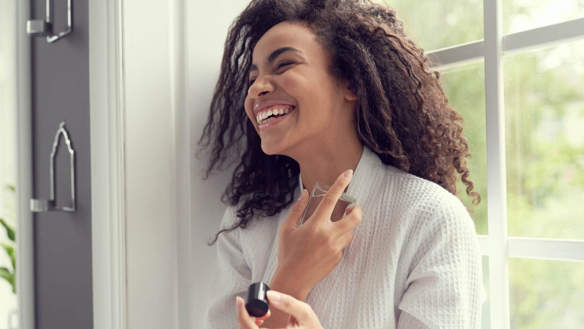 Happy woman applies perfume showing way to attract men