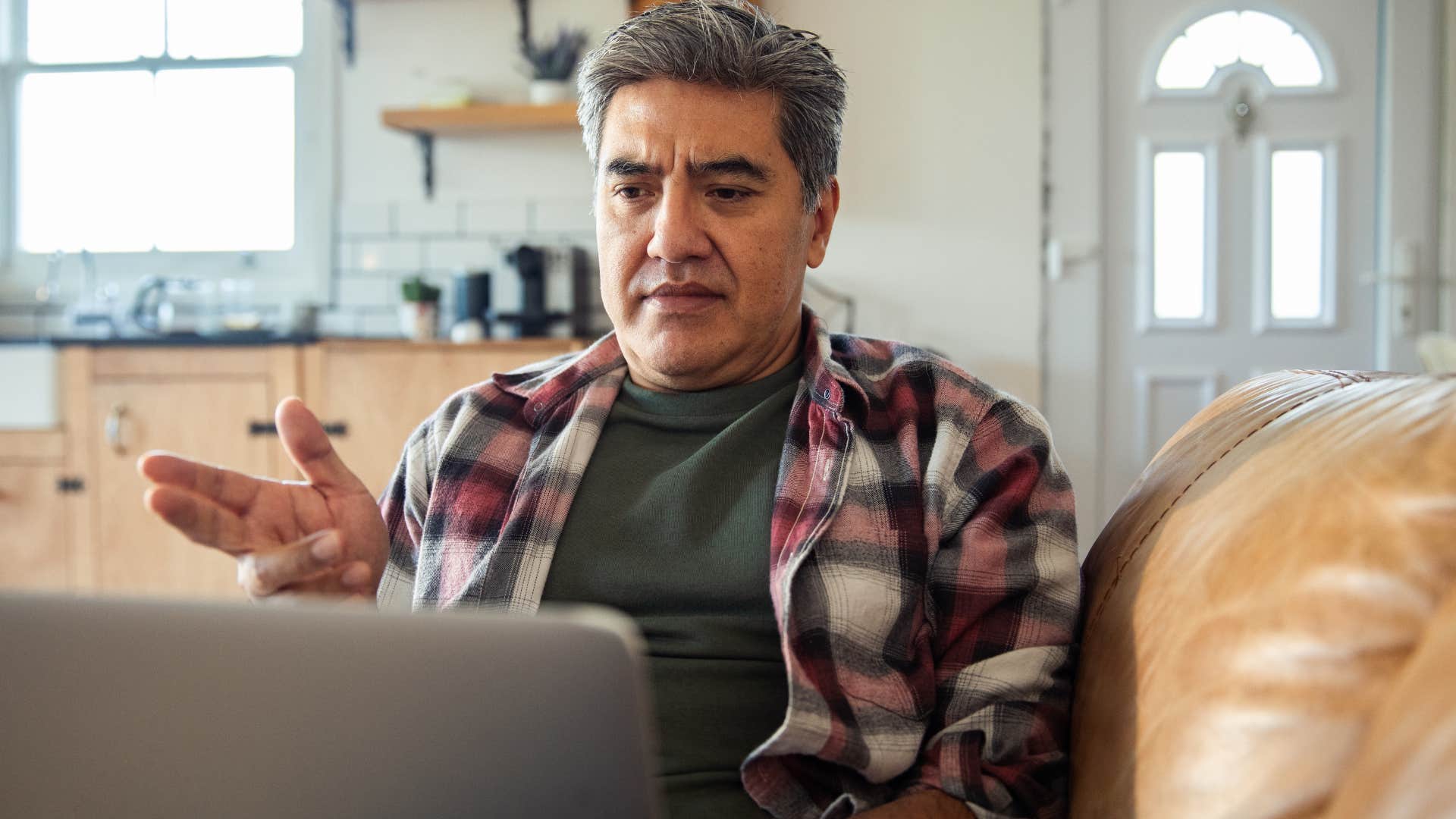 Man who's comfortable with discomfort talking on his laptop.