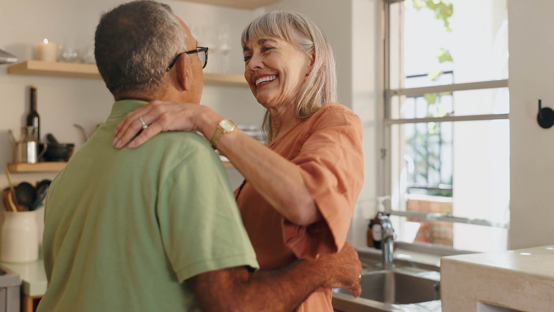 man reassuring wife through actions in the kitchen