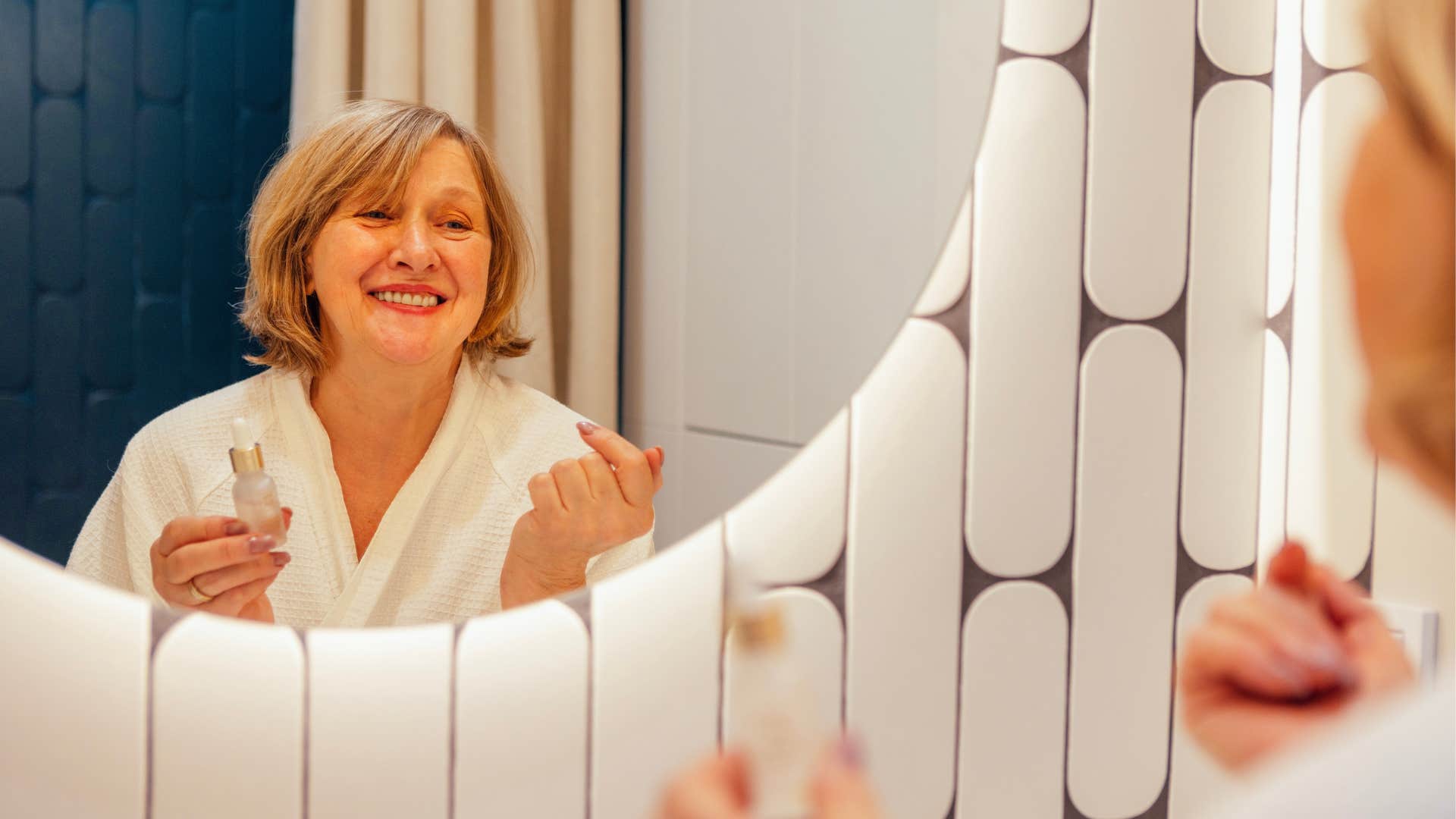 Woman who knows how to self-soothe smiling in a mirror.