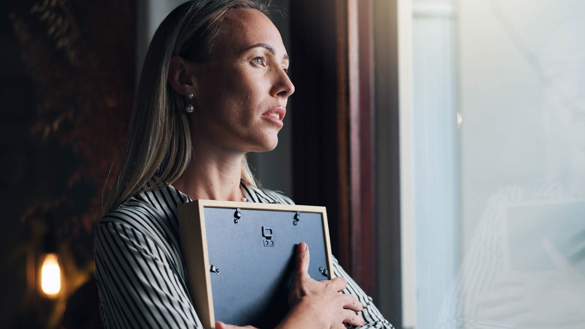 woman holding picture frame comforting herself during hardship