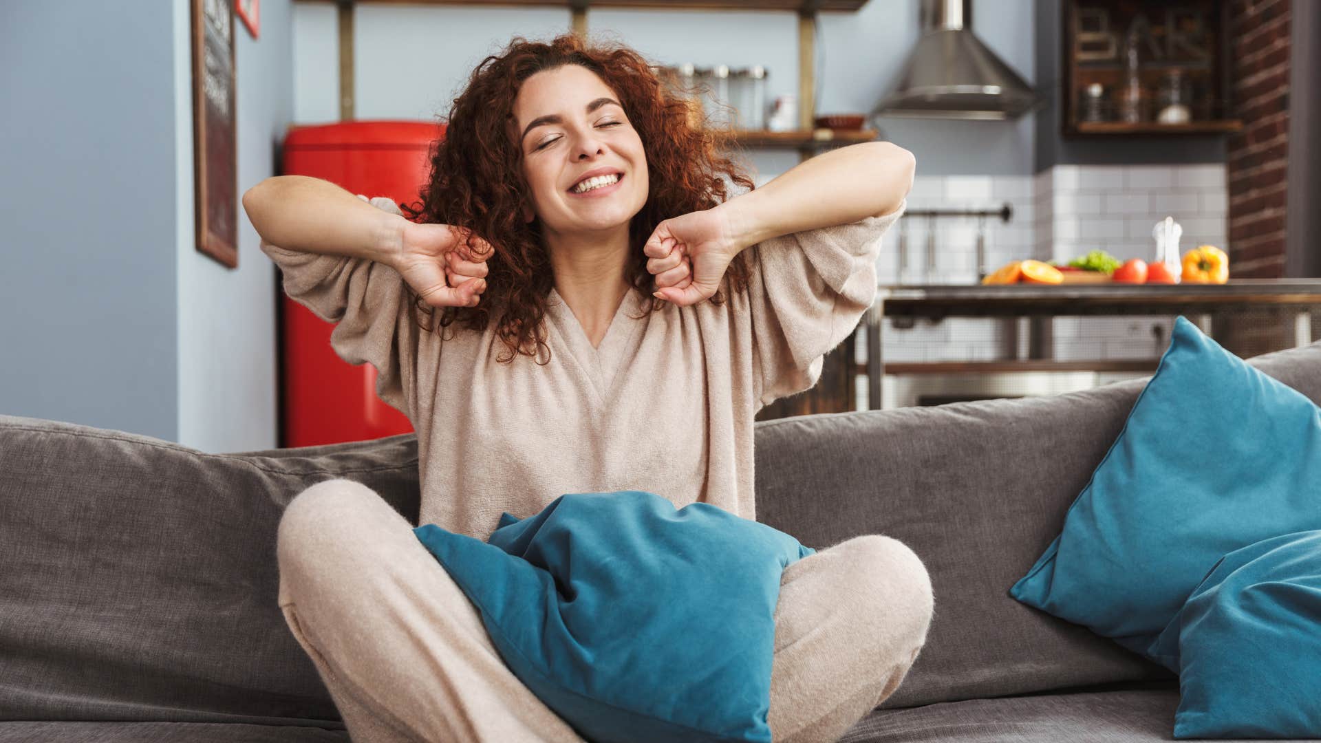 Peaceful woman on couch stretches arms showing being single is OK