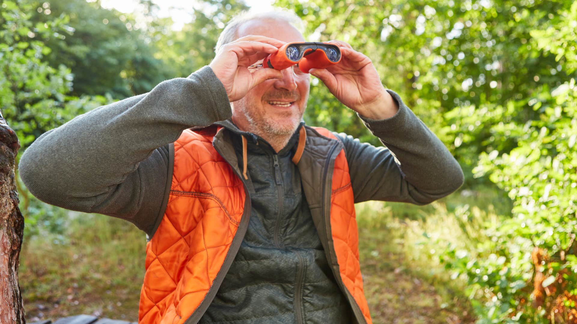 man looking at birds through binoculars