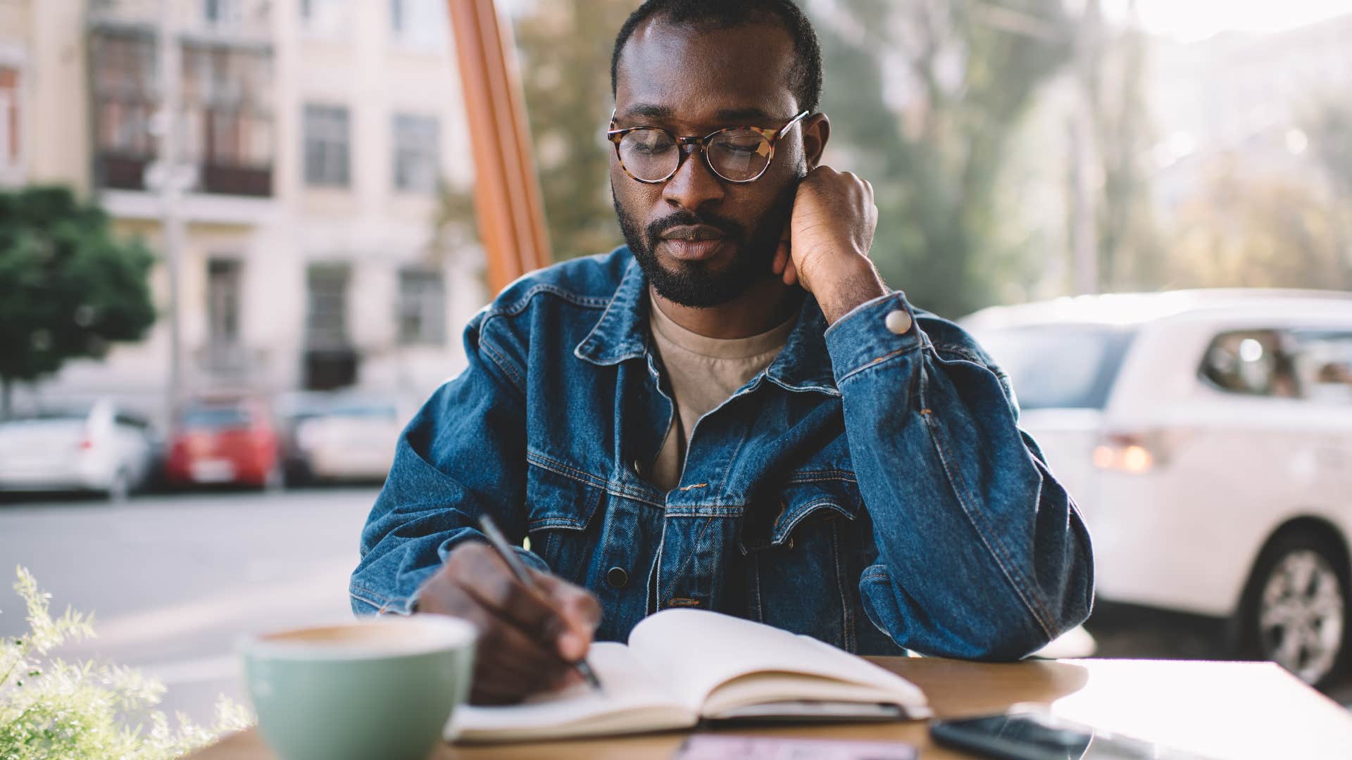 man sitting outside writing in journal