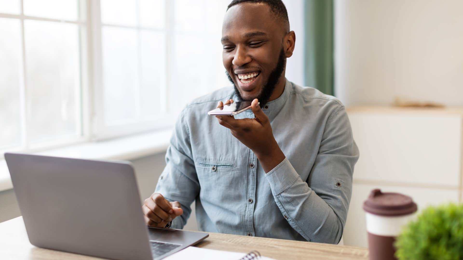 man speaking into phone while working on laptop