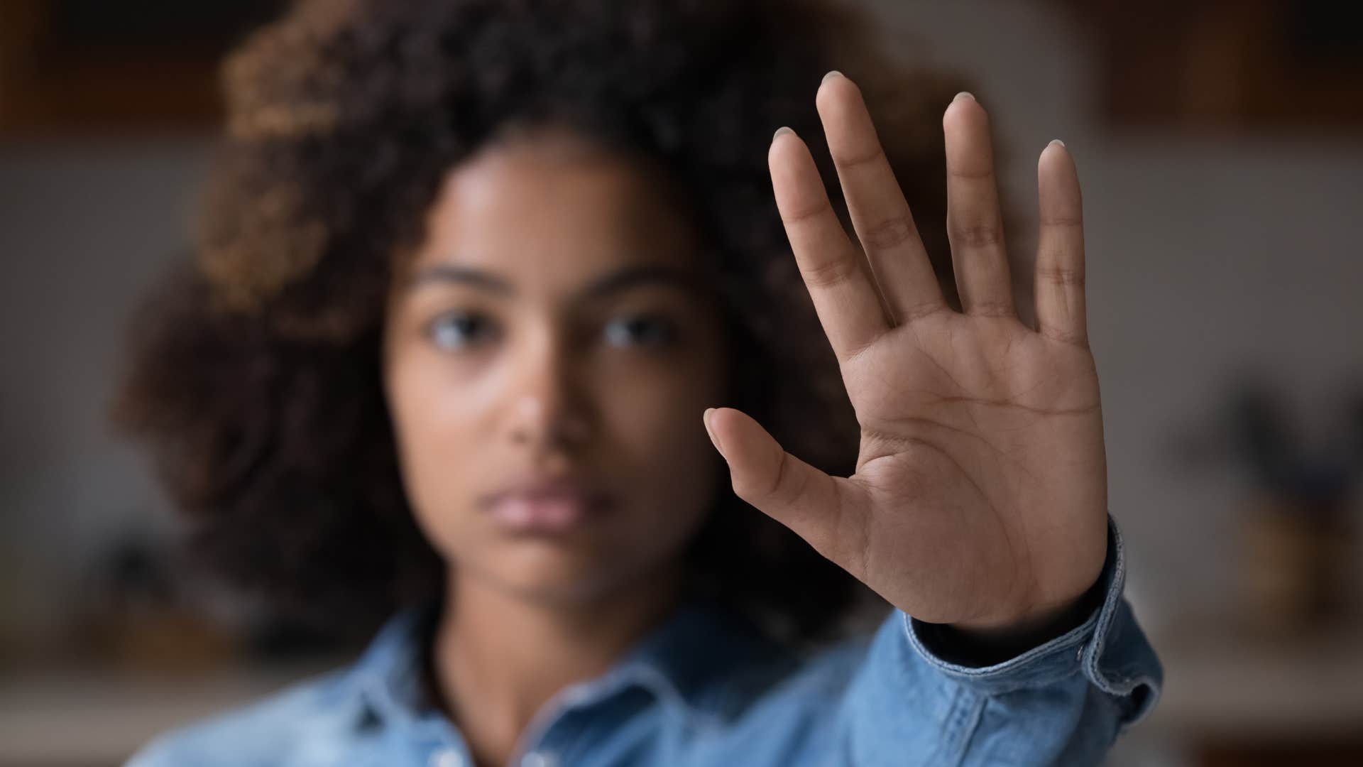Closed off woman puts up hand to say stop showing unlikable trait