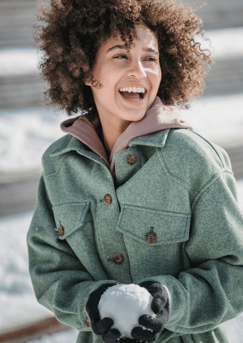 young woman holding snowball having fun