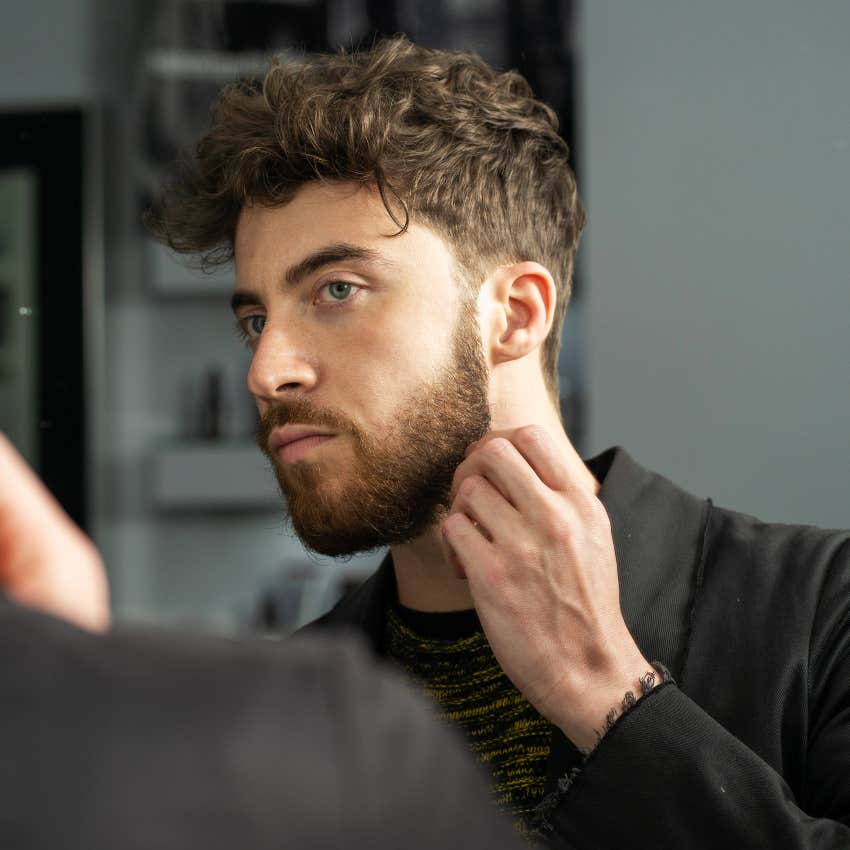 young man examining beard in mirror