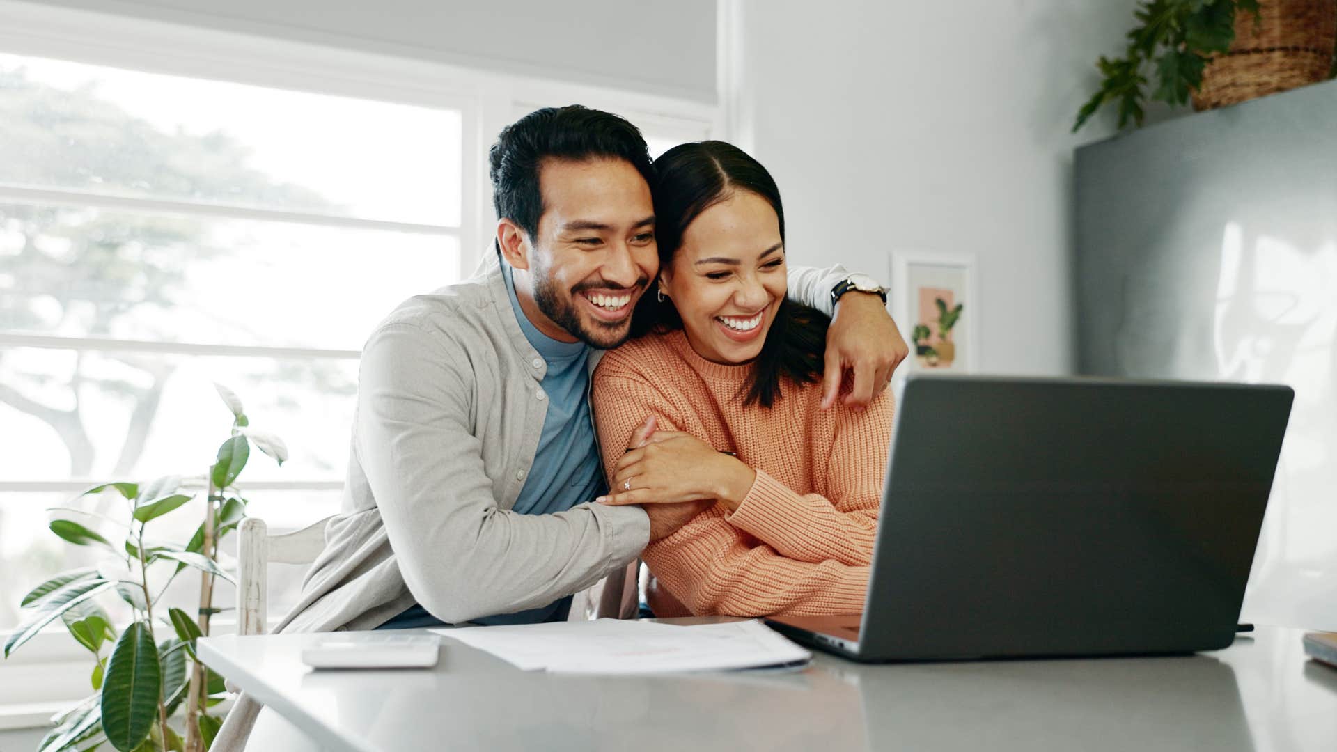 couple laughing while using laptop man telling wife i learn a lot from you
