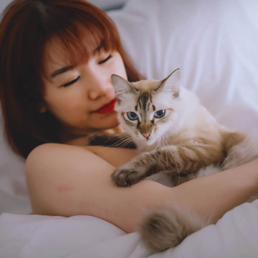 woman snuggling with her purring cat