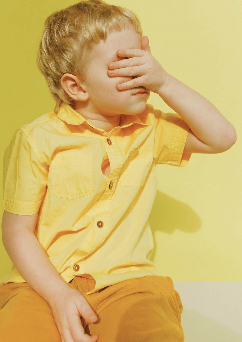 embarrassed young child covering his face
