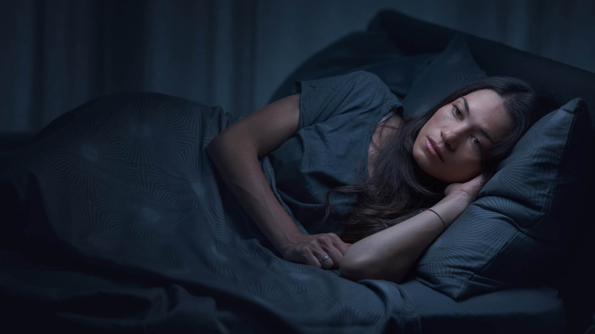 woman with adhd traits lying wide awake in bed hearing snoring