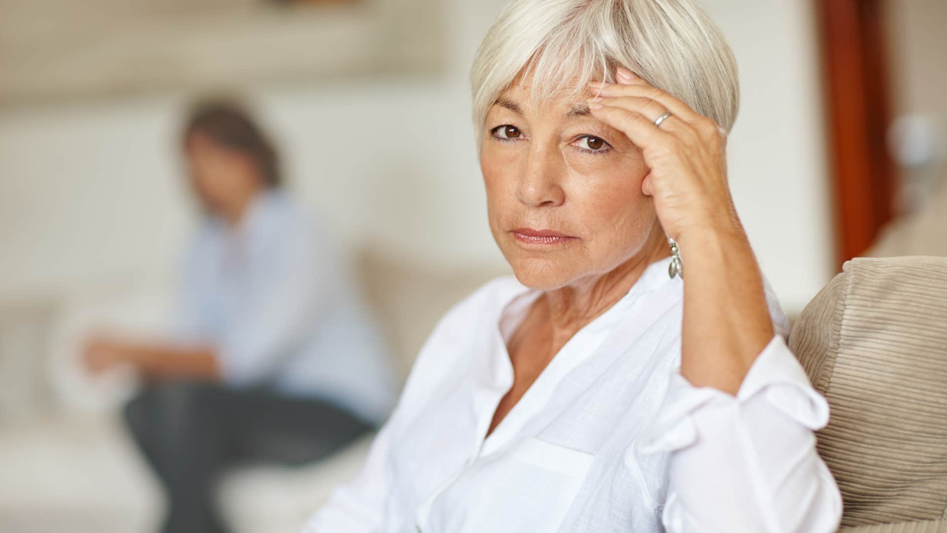 older annoyed woman sitting away from partner tapping their foot