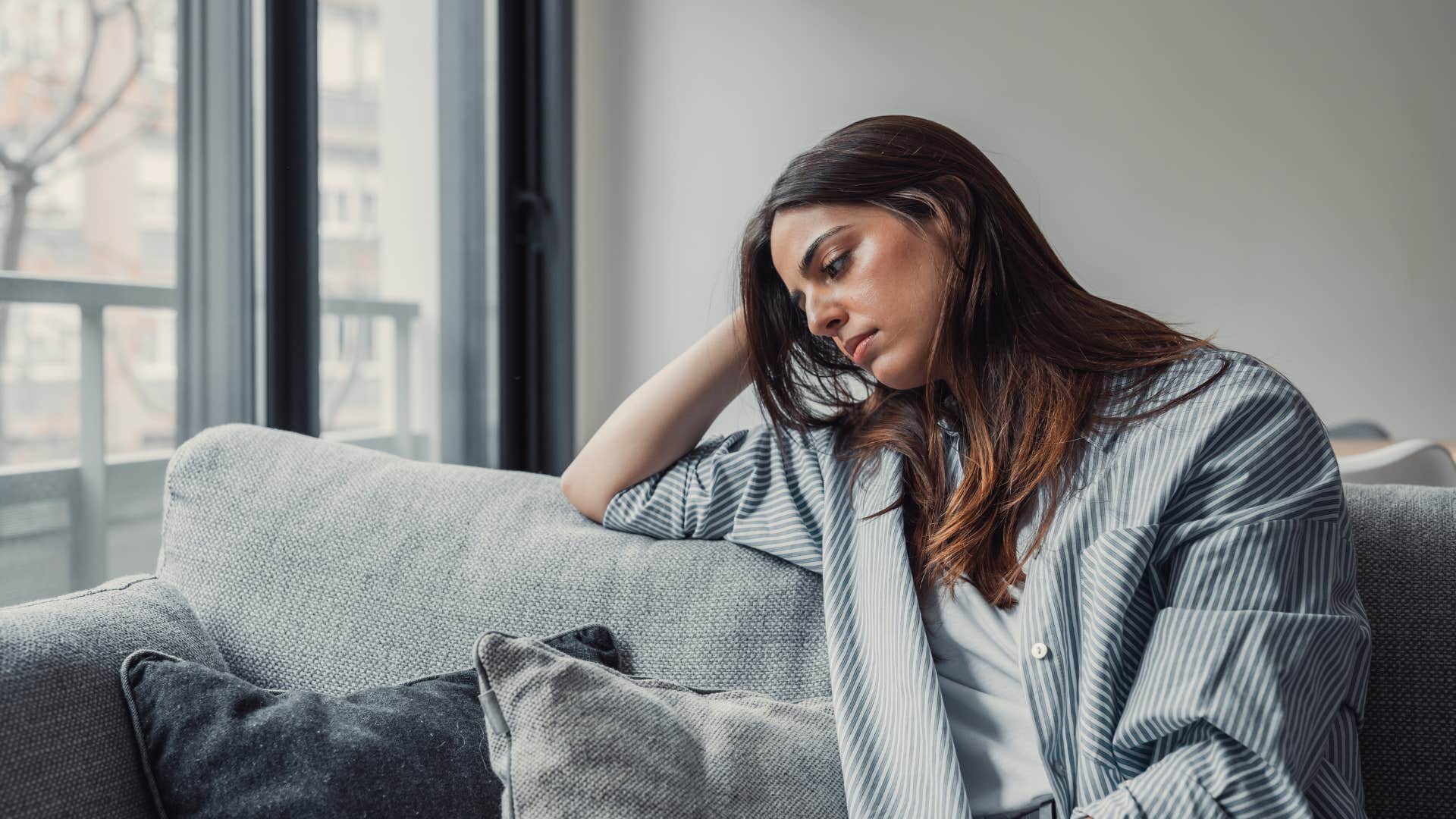 tired woman sitting on couch hearing whistling outside