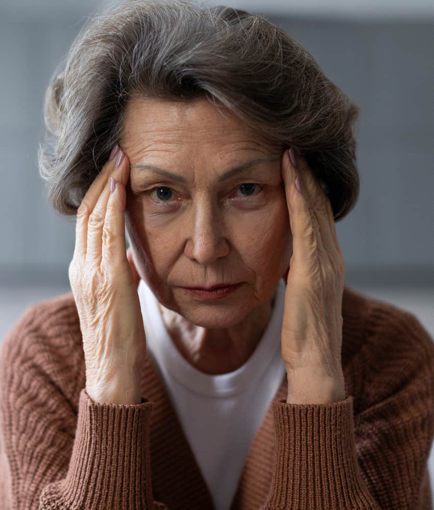 upset older person touches sides of head showing they hold negativity