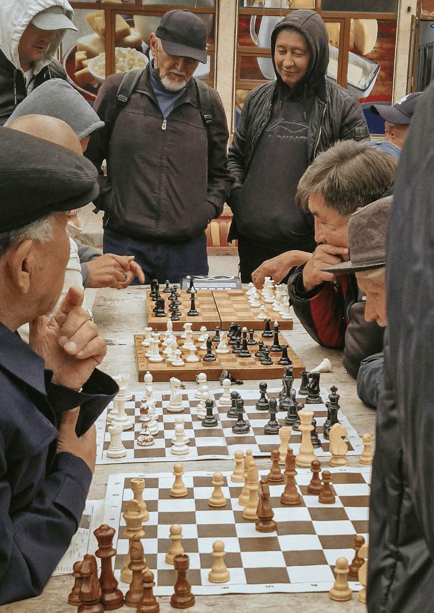 group of older men playing chess in park
