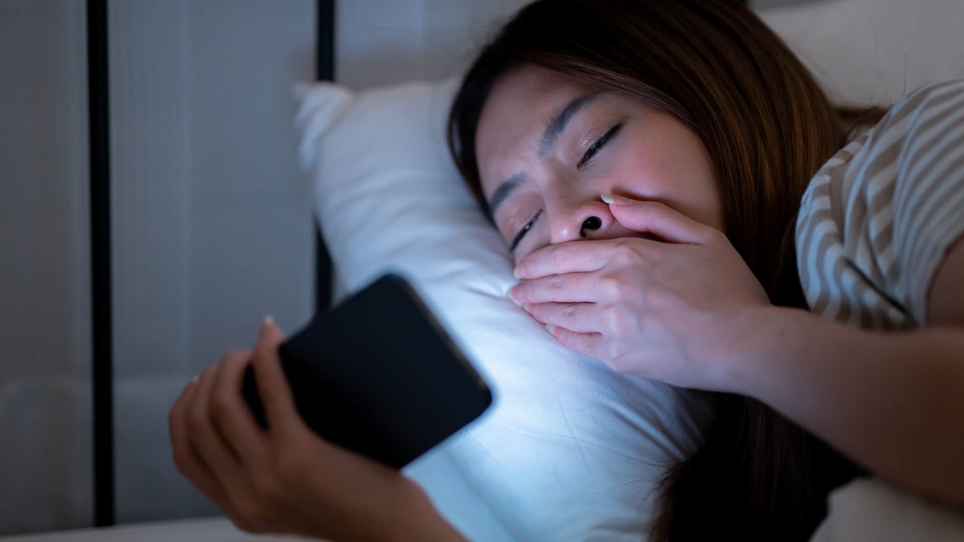 yawning woman on her phone craving stimulation at night
