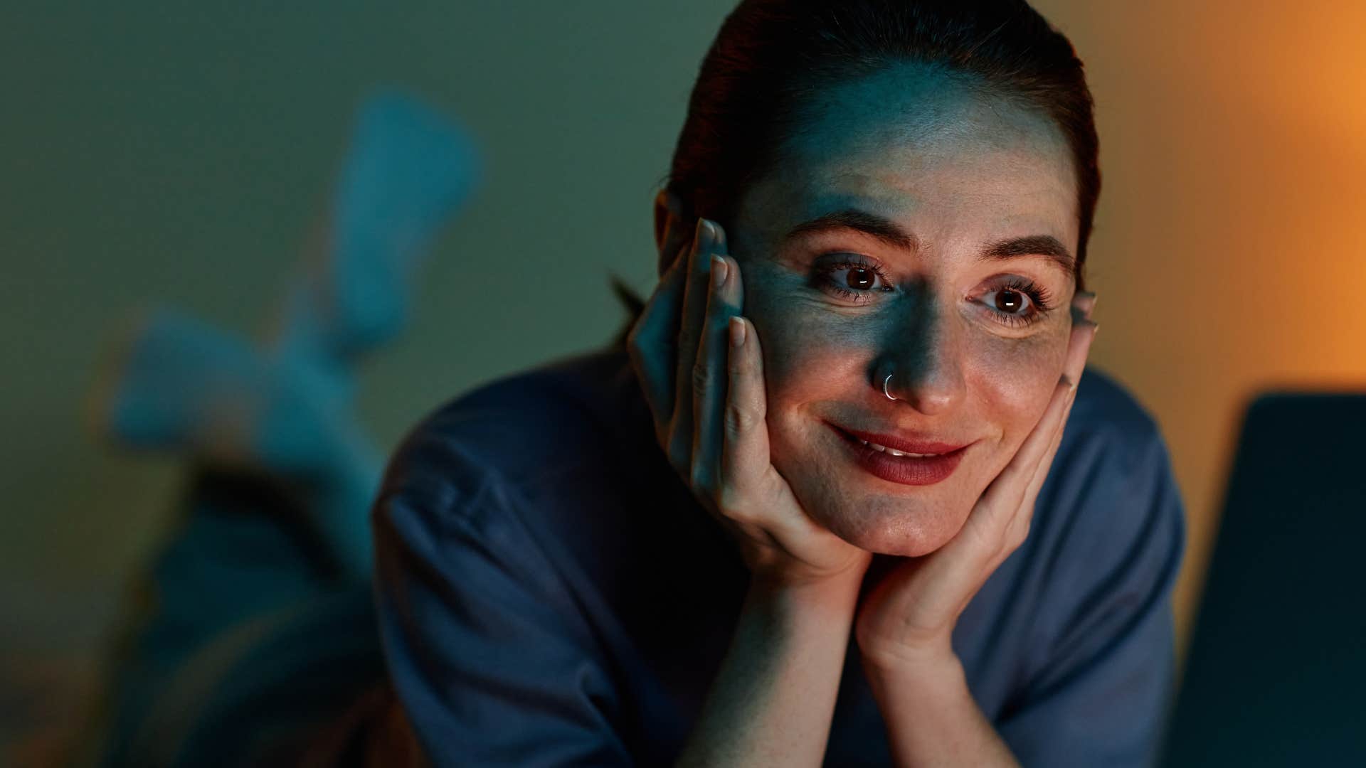 smiling but tired woman who romanticizes late nights at home