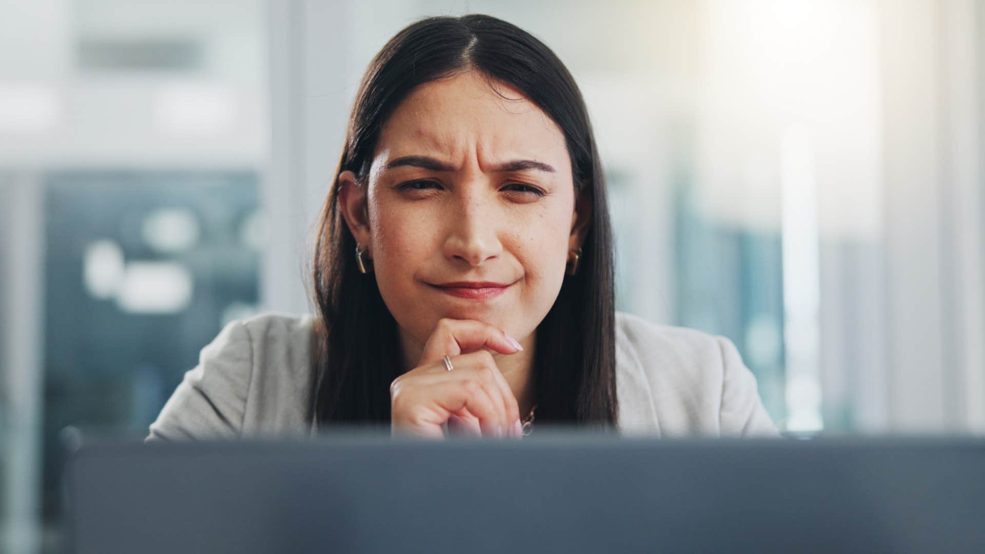 Woman who's a deep thinker looking at her laptop.