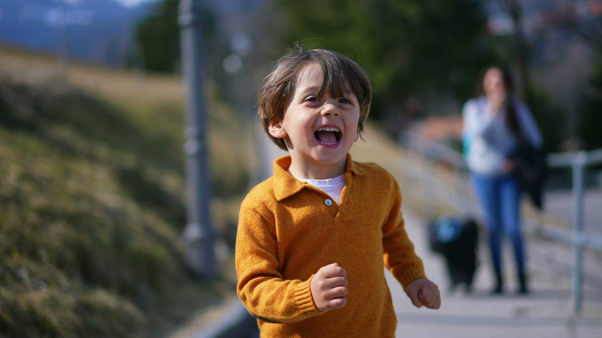 Joyful boy running in front of parent