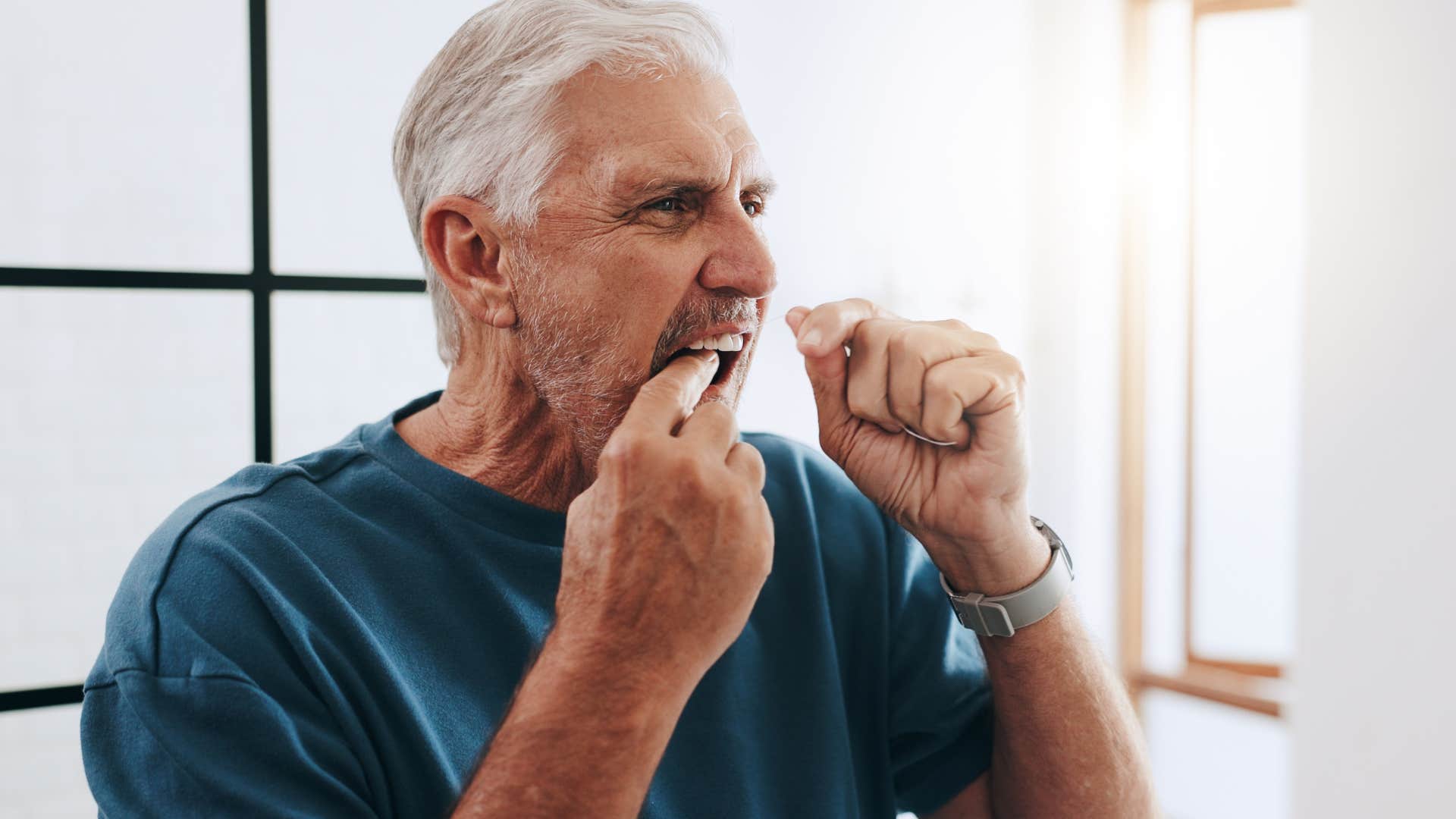 man flossing his teeth at home
