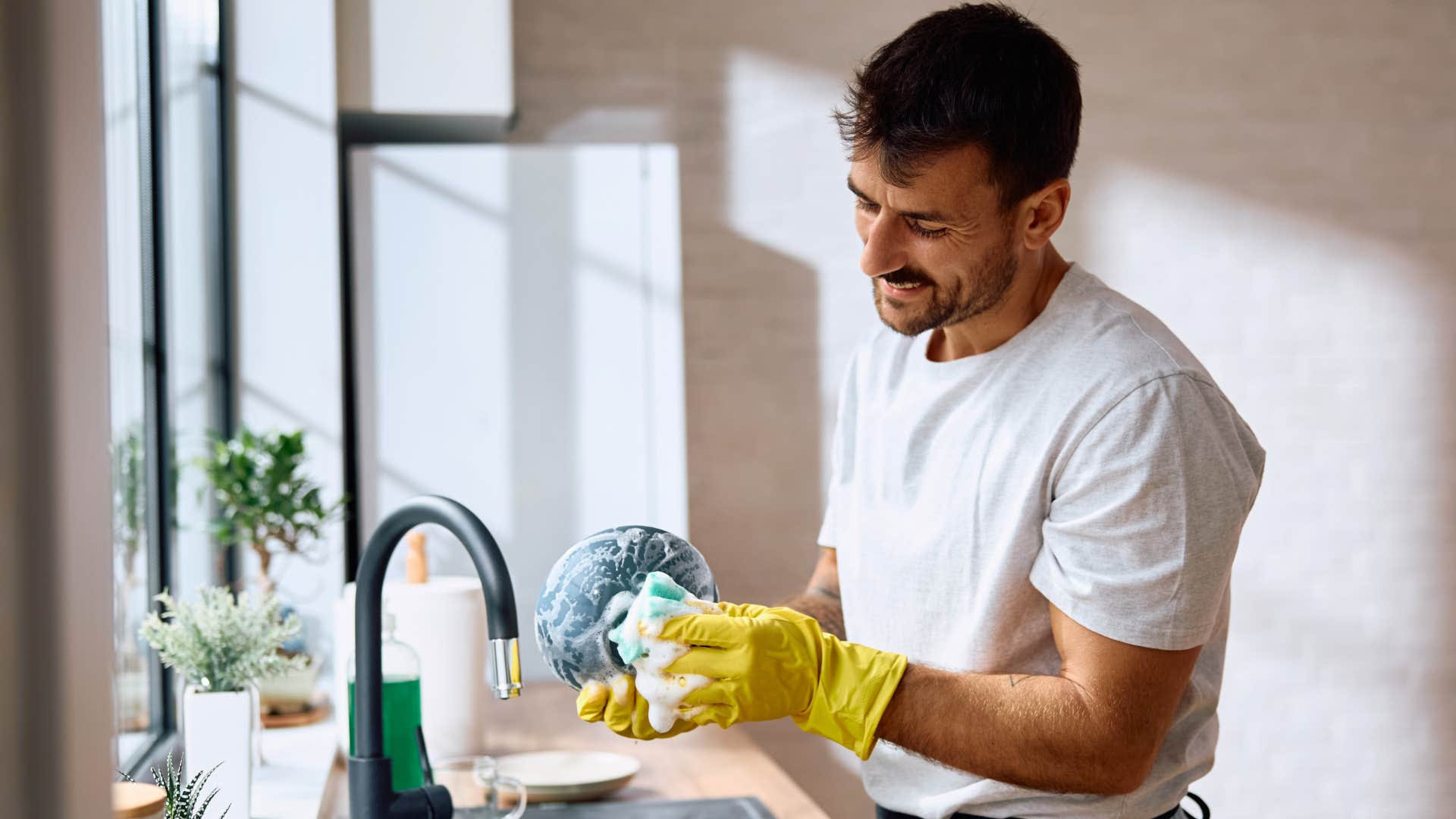 man using dirty sponges to clean dishes at home