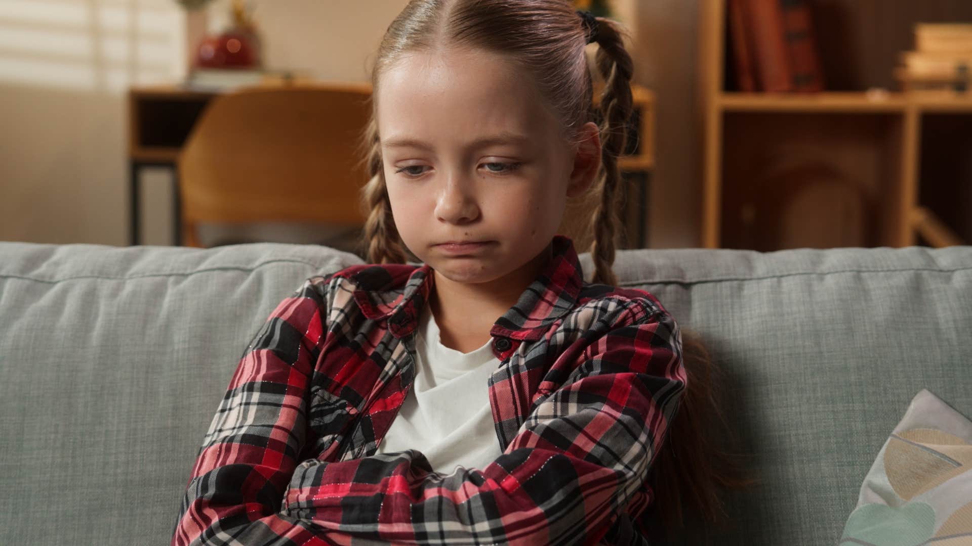 upset little girl sitting on couch