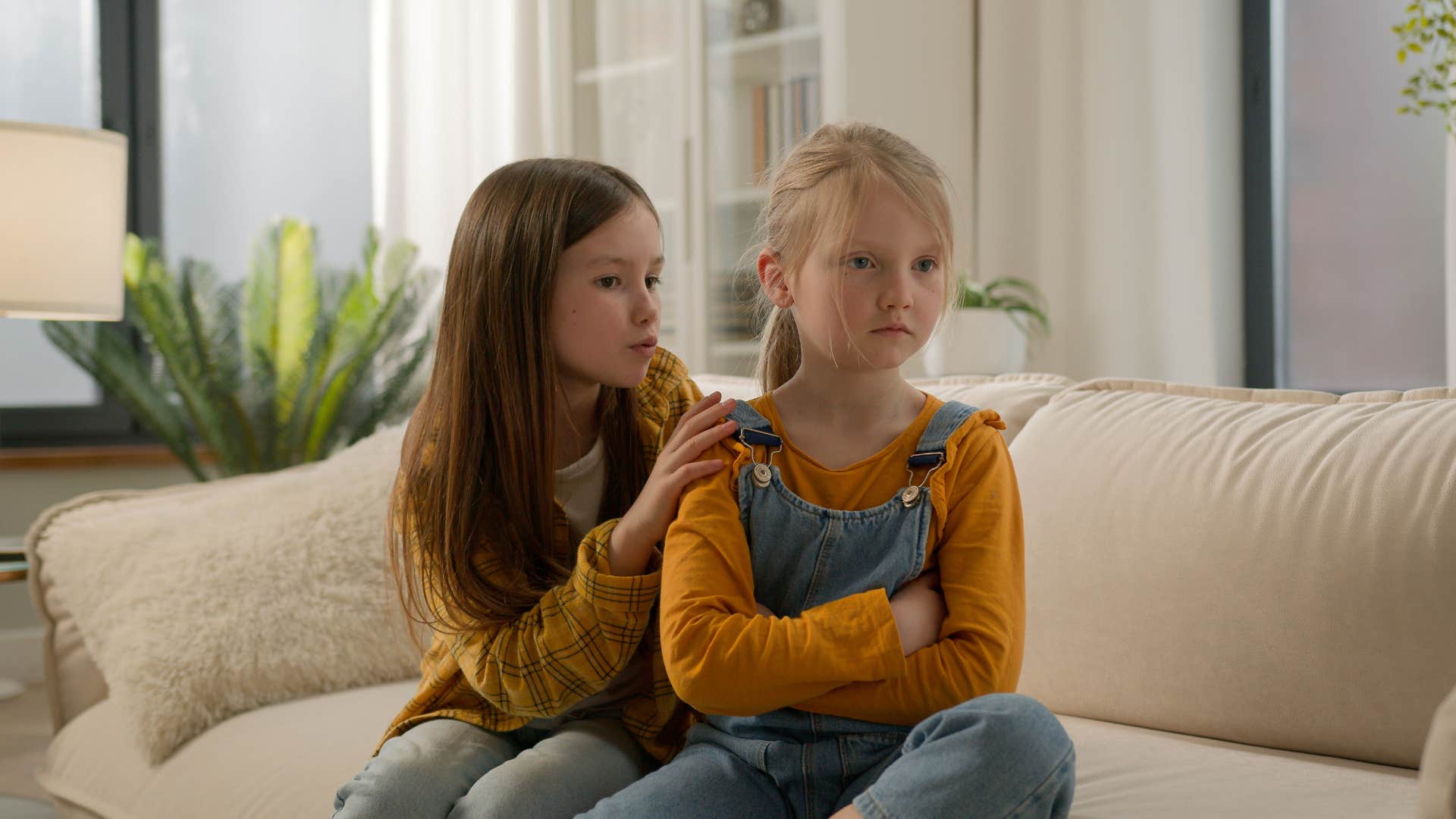 two girls having disagreement sitting on couch at home