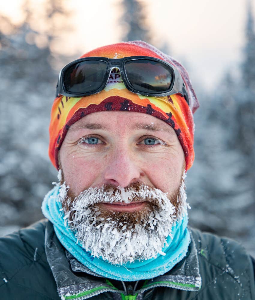 man in forest with snow in beard showing he has embraced isolation