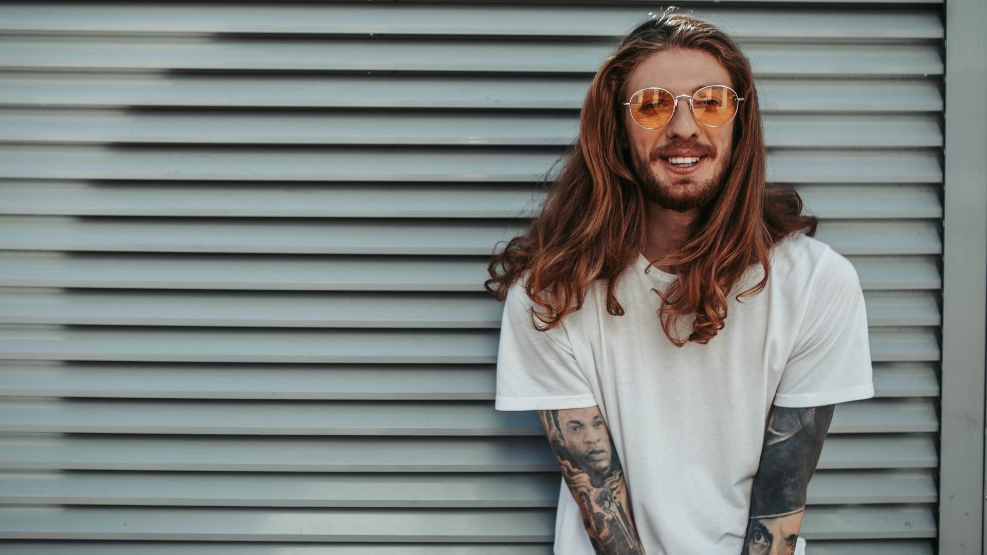 confident man with tattoos standing outside