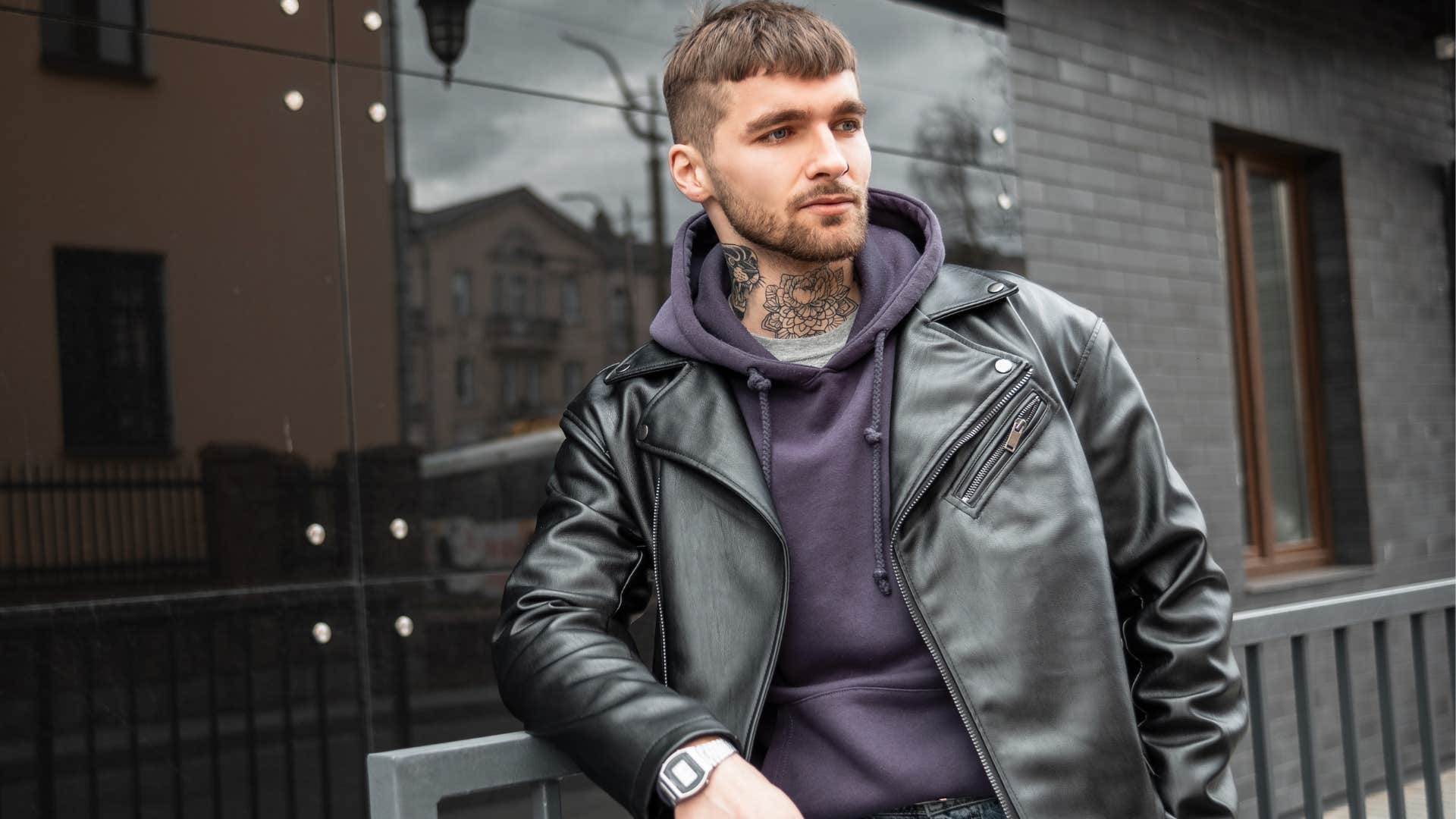 self-aware tattooed man standing alone outside thinking