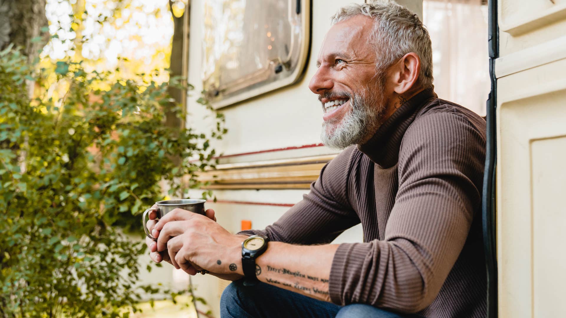 unique older man with tattoos smiling with coffee outside