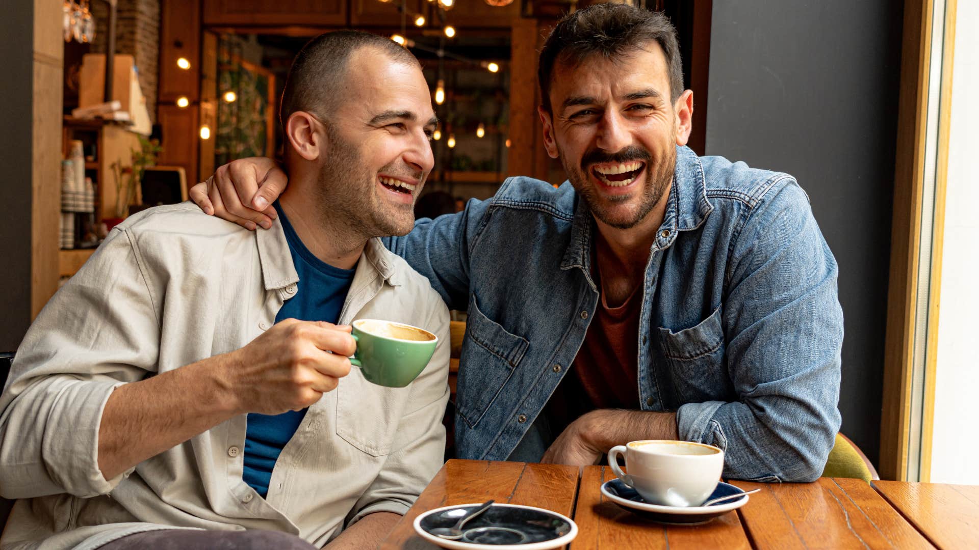 two men skilled at maintaining their friendship laughing while eating at cafe