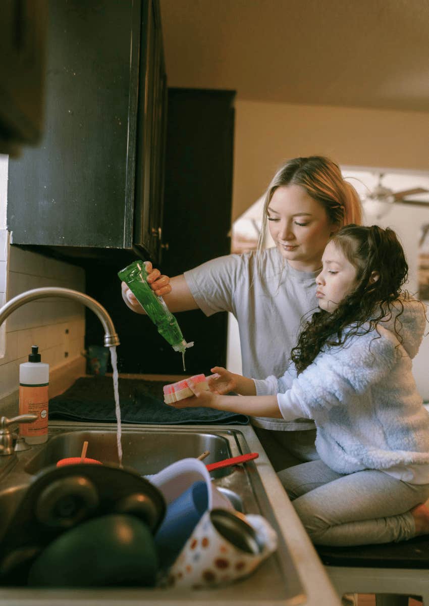 mom helping child wash the dishes