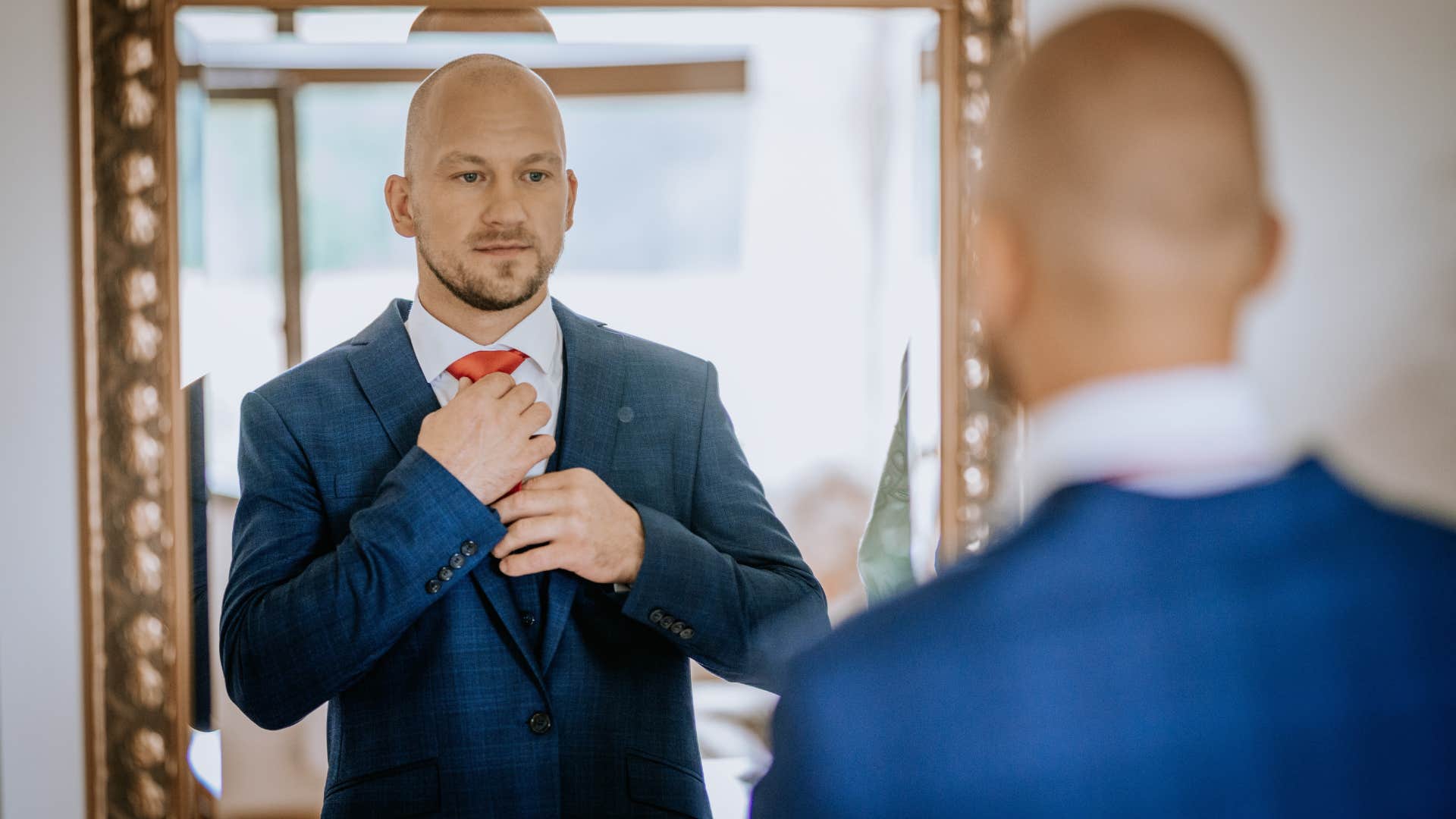 man putting on tie in mirror acting like a pretty boy
