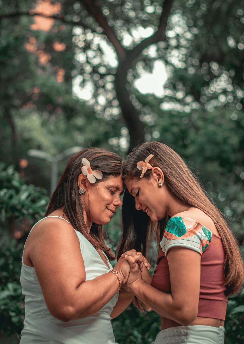 mother and adult daughter holding hands standing close