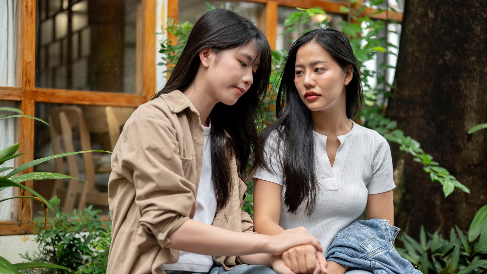 friends talking seriously on bench as woman with tan jacket says i feel hurt by that even if it wasn't your intention