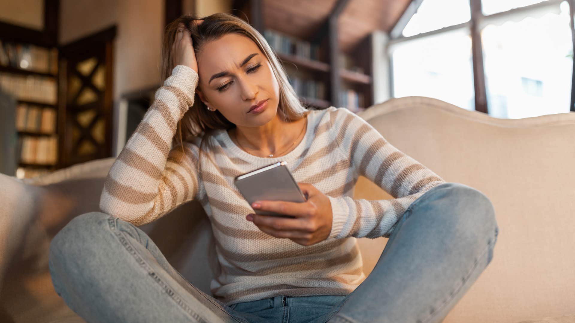 woman in stripped shirt looking at phone and thinking i need clarity before i can move forward