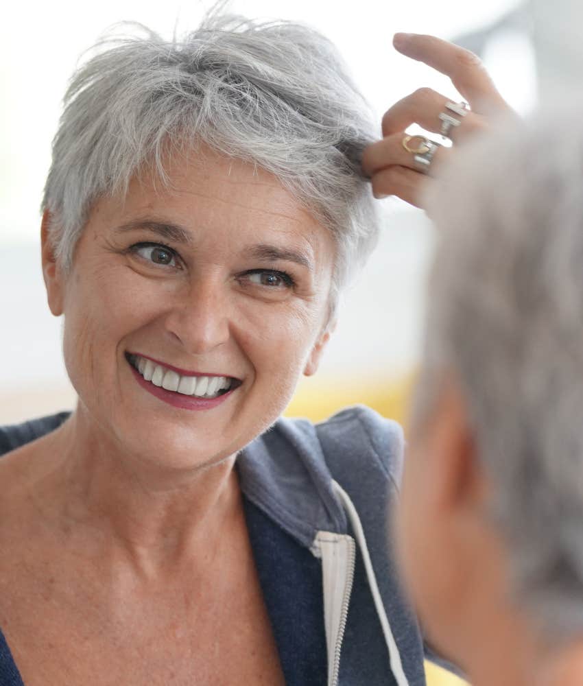 older woman looks in mirror 