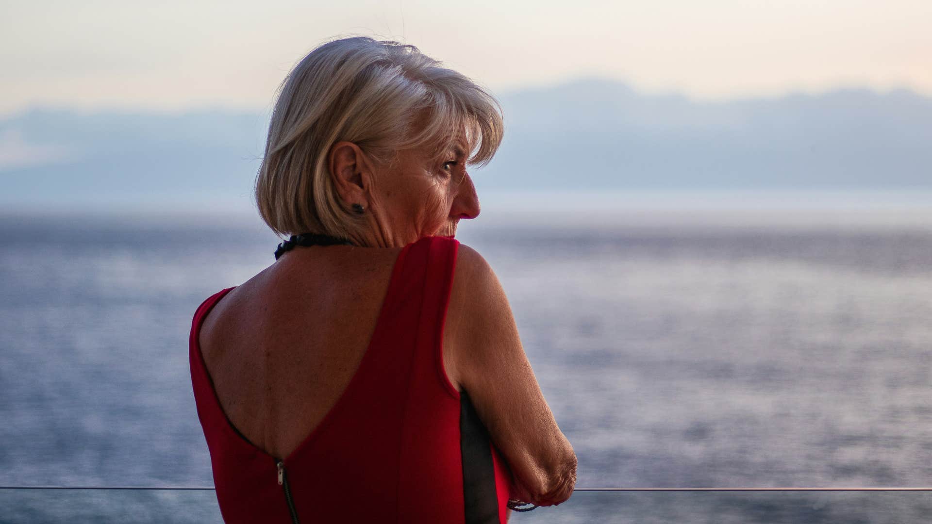 introspective older woman looks at ocean showing feeling of home